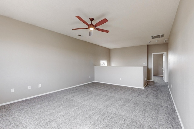 empty room featuring carpet flooring, a ceiling fan, visible vents, and baseboards