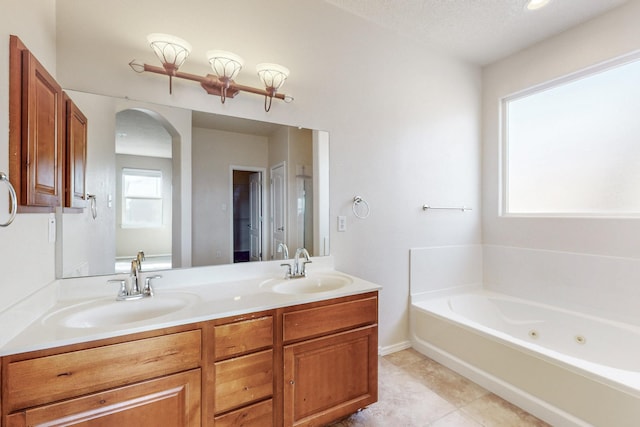 full bathroom with double vanity, a jetted tub, tile patterned floors, and a sink