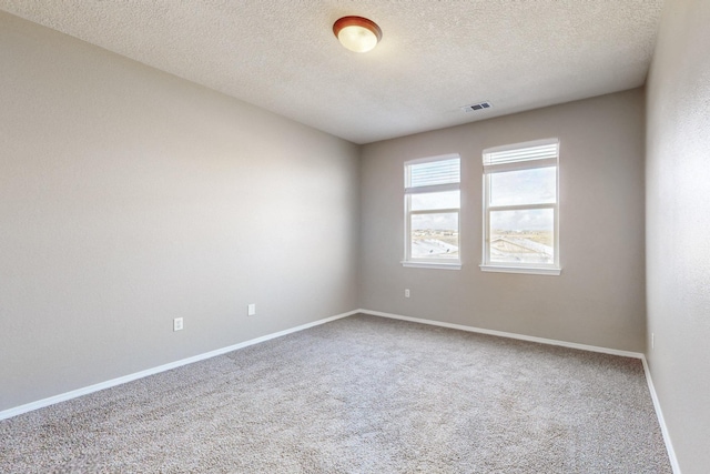 carpeted spare room with visible vents, baseboards, and a textured ceiling