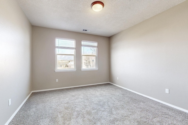 empty room with visible vents, carpet flooring, a textured ceiling, and baseboards