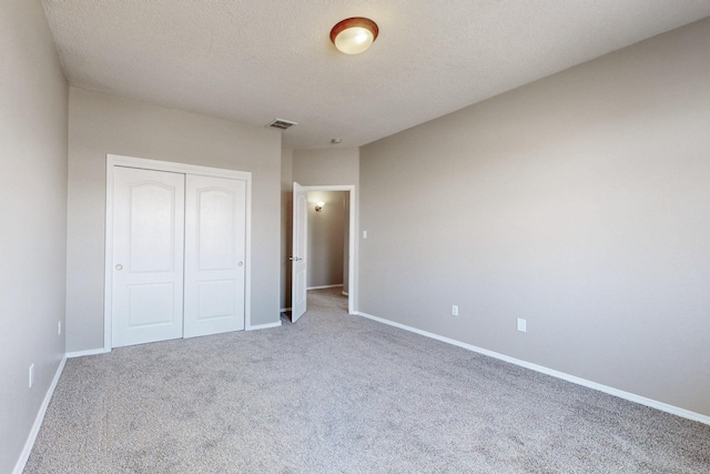 unfurnished bedroom with visible vents, baseboards, carpet floors, a closet, and a textured ceiling