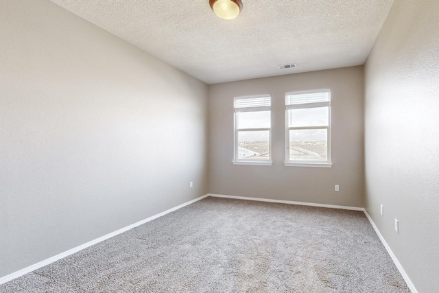 carpeted empty room with visible vents, a textured ceiling, and baseboards