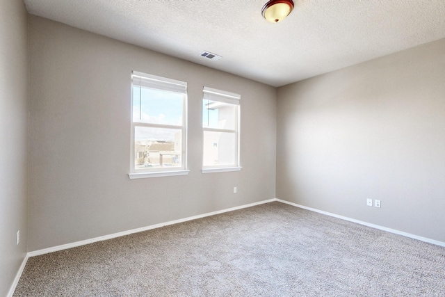 carpeted empty room with visible vents, baseboards, and a textured ceiling