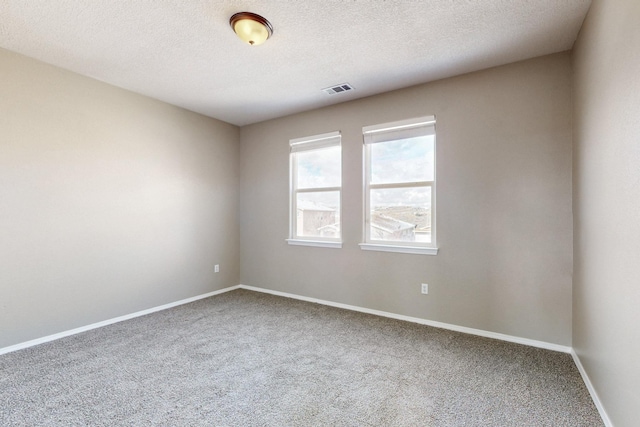 carpeted spare room with visible vents, baseboards, and a textured ceiling