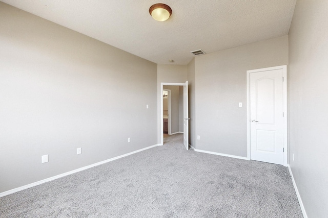 carpeted spare room featuring visible vents, baseboards, and a textured ceiling