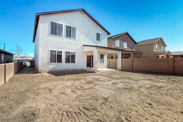 rear view of house with a patio, a fenced backyard, and stucco siding