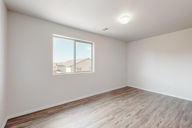 spare room with light wood-style flooring, visible vents, and baseboards