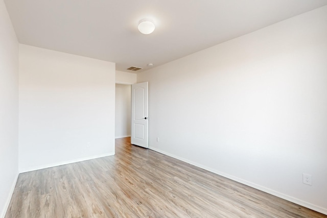 spare room with light wood-style floors, visible vents, and baseboards