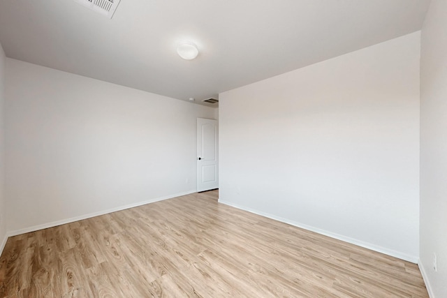 empty room featuring visible vents, baseboards, and light wood finished floors