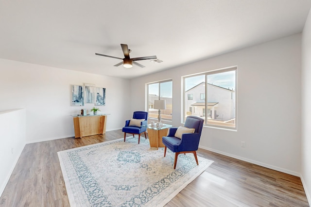 living area with visible vents, baseboards, wood finished floors, and a ceiling fan