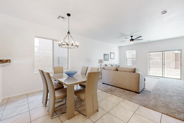 dining space with visible vents, baseboards, light carpet, light tile patterned floors, and ceiling fan with notable chandelier