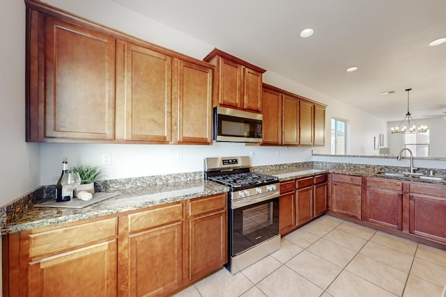 kitchen with a sink, light stone counters, decorative light fixtures, stainless steel appliances, and light tile patterned floors