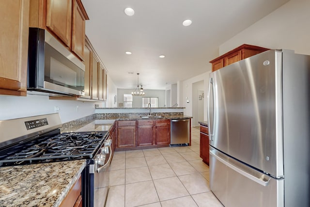 kitchen with a sink, stainless steel appliances, a peninsula, light tile patterned flooring, and light stone countertops