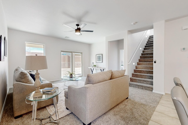 living room with stairway, light tile patterned floors, a ceiling fan, visible vents, and baseboards