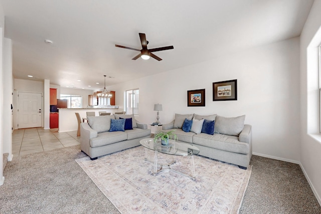 living room featuring light tile patterned floors, baseboards, recessed lighting, light carpet, and ceiling fan with notable chandelier