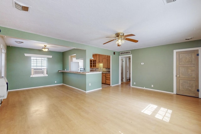 unfurnished living room featuring light wood-type flooring, visible vents, ceiling fan, and baseboards