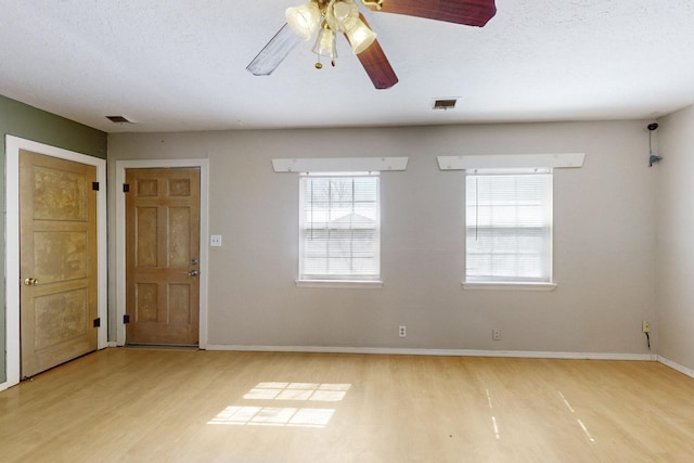 spare room with baseboards, visible vents, ceiling fan, and wood finished floors