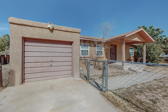 view of front of house featuring a garage, driveway, a gate, fence, and stucco siding