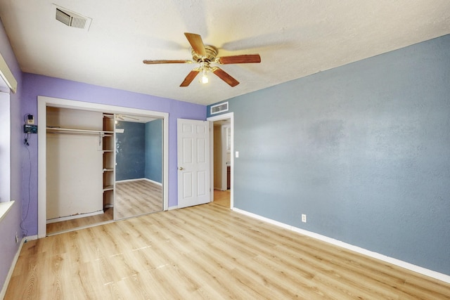 unfurnished bedroom with a closet, visible vents, baseboards, and wood finished floors