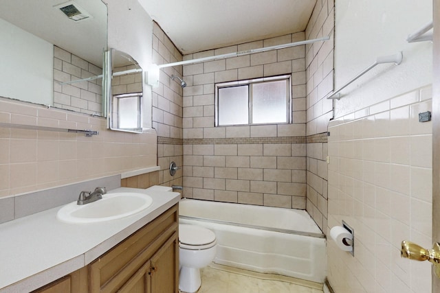 full bath featuring shower / bath combination, visible vents, toilet, vanity, and tile walls