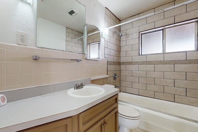 full bathroom featuring shower / bathtub combination, toilet, visible vents, vanity, and tile walls