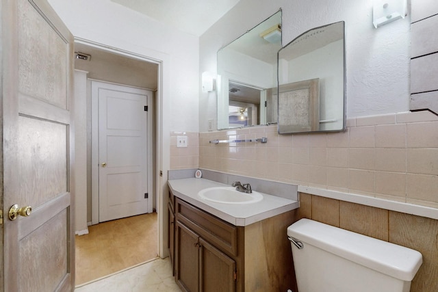 bathroom with tile walls, visible vents, backsplash, toilet, and vanity