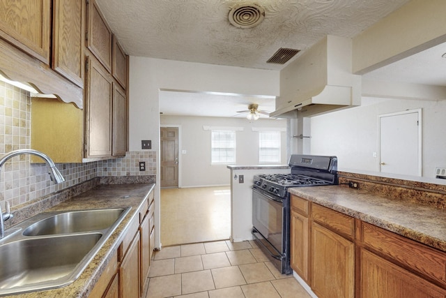 kitchen featuring tasteful backsplash, black range with gas stovetop, a sink, and visible vents