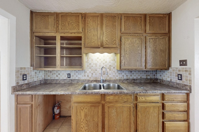 kitchen with open shelves, decorative backsplash, light tile patterned flooring, a sink, and a textured ceiling