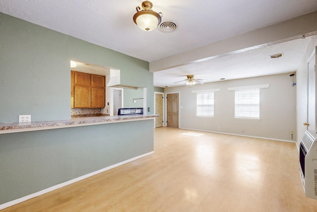 kitchen with visible vents, light countertops, brown cabinets, heating unit, and light wood finished floors