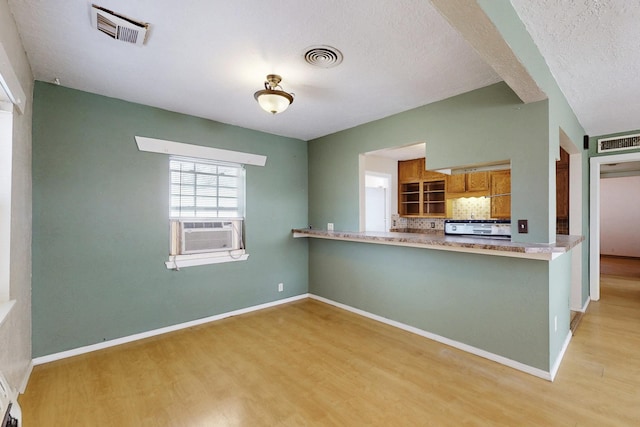 kitchen featuring brown cabinets, light wood-type flooring, visible vents, and decorative backsplash