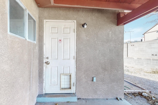 property entrance with fence and stucco siding