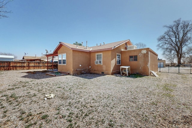 back of property with cooling unit, crawl space, fence, and stucco siding