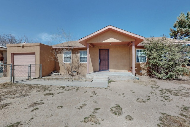 view of front of house with a garage, fence, a gate, and stucco siding