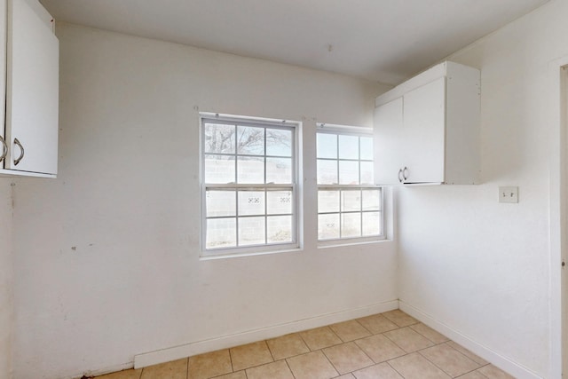 spare room with light tile patterned flooring and baseboards