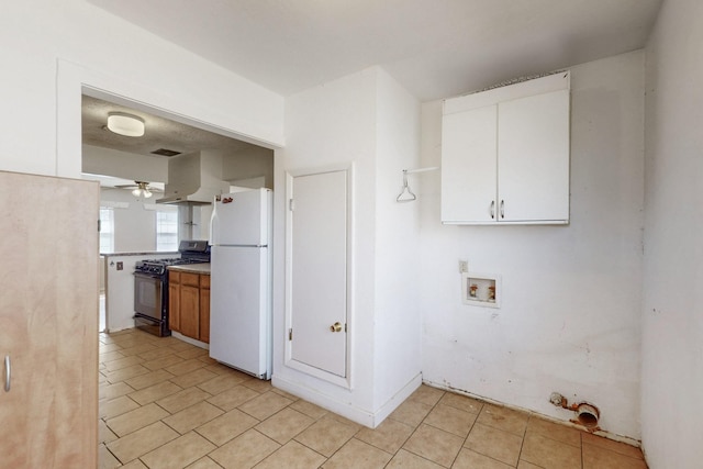 kitchen featuring ceiling fan, white cabinets, wall chimney range hood, freestanding refrigerator, and gas range oven