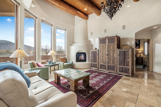 living room with a fireplace, stone tile flooring, a mountain view, wooden ceiling, and beamed ceiling