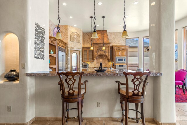 kitchen with a peninsula, tasteful backsplash, glass insert cabinets, and built in appliances