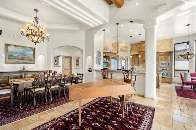 dining room with stone tile floors, arched walkways, a high ceiling, a chandelier, and recessed lighting