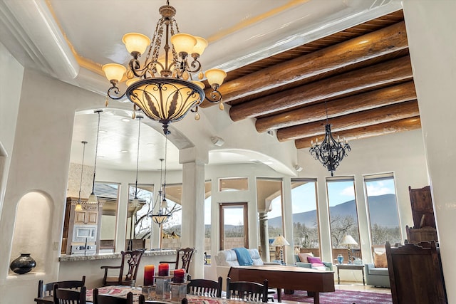 interior space with arched walkways, a notable chandelier, beamed ceiling, and a mountain view