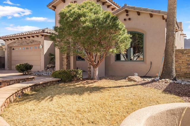 view of front of home featuring a garage, a tile roof, and stucco siding