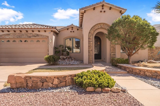 mediterranean / spanish home with a garage, a tile roof, concrete driveway, and stucco siding