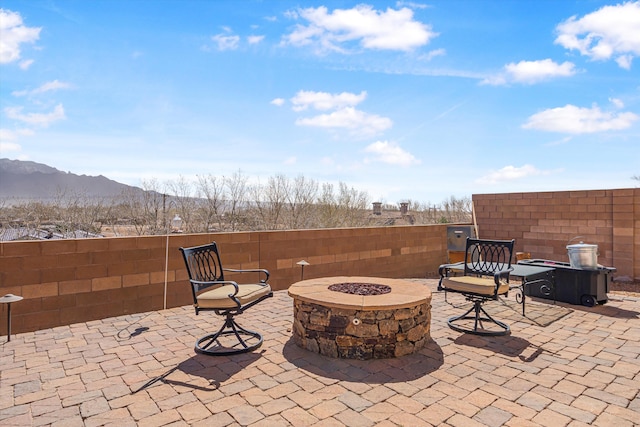 view of patio / terrace featuring an outdoor fire pit, fence, and a mountain view