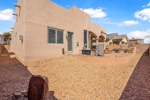 rear view of house featuring a patio area, fence, and stucco siding