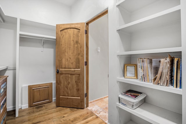 walk in closet with light wood finished floors