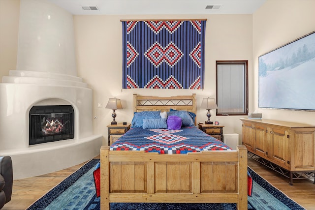 bedroom featuring a fireplace, visible vents, and wood finished floors