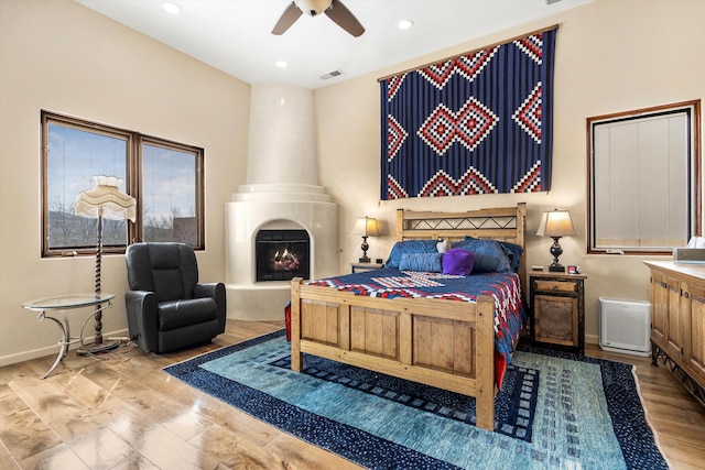 bedroom with baseboards, ceiling fan, wood finished floors, a fireplace, and recessed lighting