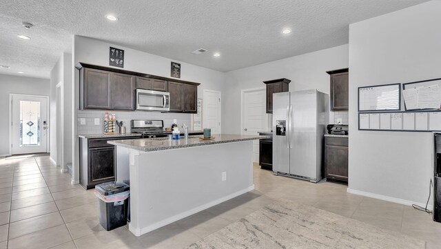 889 Tazanita Loop SE, Rio Rancho, NM 87124 - kitchen featuring stainless steel appliances, dark brown cabinetry, a textured ceiling, a kitchen island with sink, and decorative backsplash