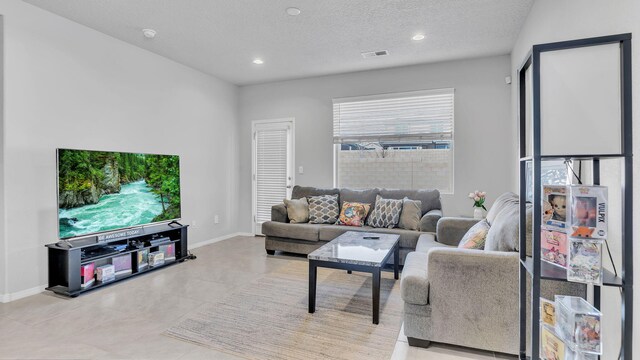 living room featuring visible vents, a textured ceiling, recessed lighting, light tile patterned floors, and baseboards