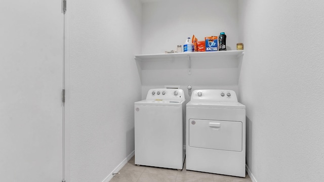 washroom with light tile patterned floors, baseboards, laundry area, and washer and clothes dryer