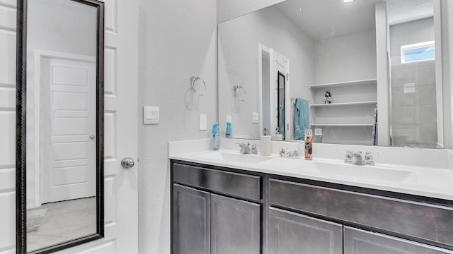 bathroom with double vanity, a textured wall, and a sink